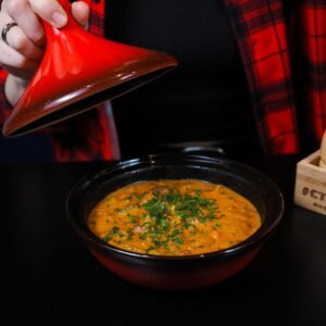 Warm, spicy lentil soup served in a ceramic bowl with herbs.