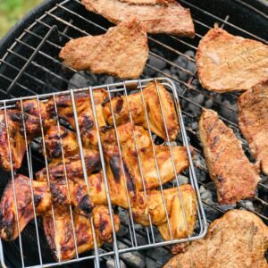 Juicy meat grilling on a charcoal barbecue outdoors, capturing summer picnic vibes.