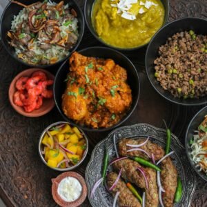 A diverse spread of Indian dishes featuring curry, meat, and sides on an intricately carved table.