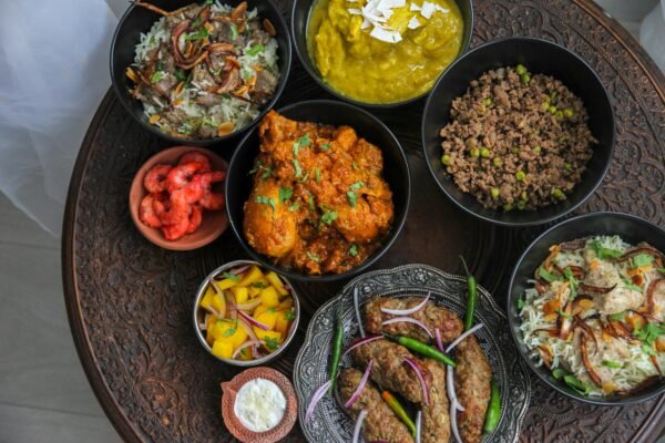 A diverse spread of Indian dishes featuring curry, meat, and sides on an intricately carved table.