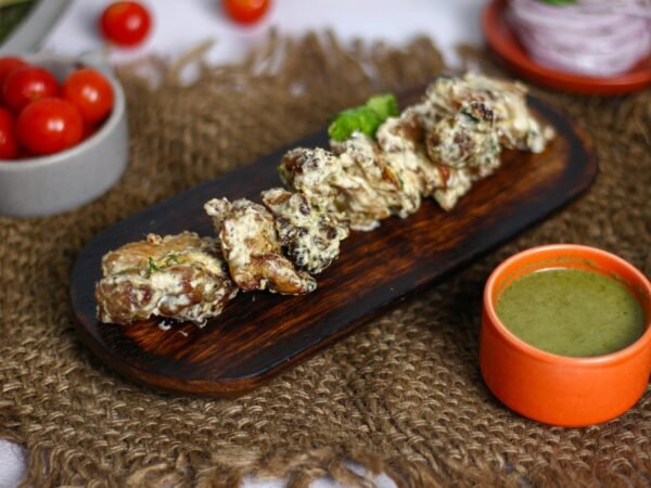 Close-up of delicious Indian Chicken Malai Tikka served with chutney on a wooden tray.