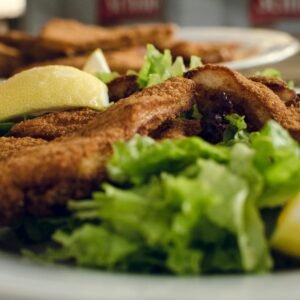 A delicious plate of crispy fried chicken served with fresh lettuce salad and lemon wedges.