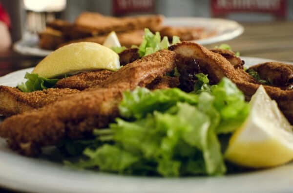 A delicious plate of crispy fried chicken served with fresh lettuce salad and lemon wedges.
